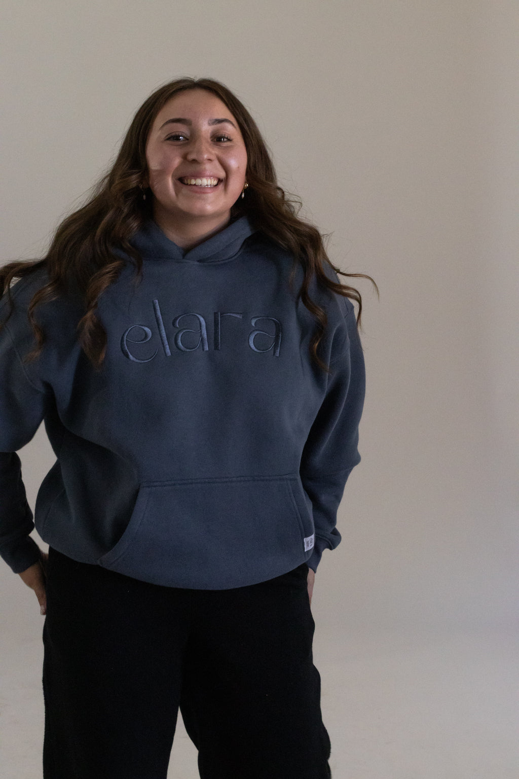 Person wearing a navy hoodie with 'elara' branding against a plain background