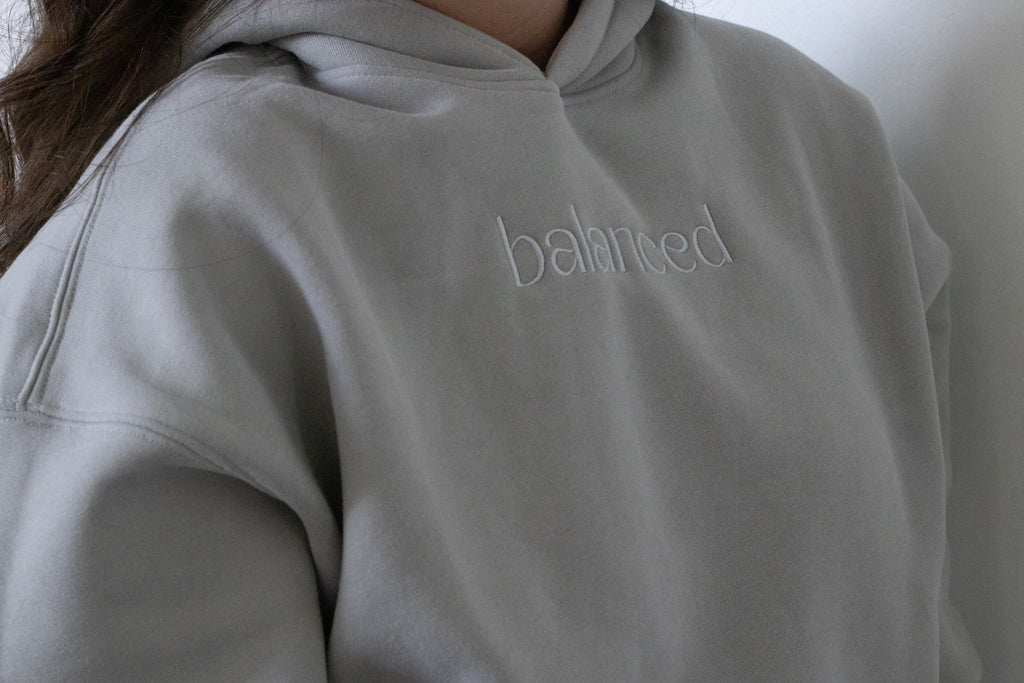 Gray hoodie with 'balanced' text on a plain background