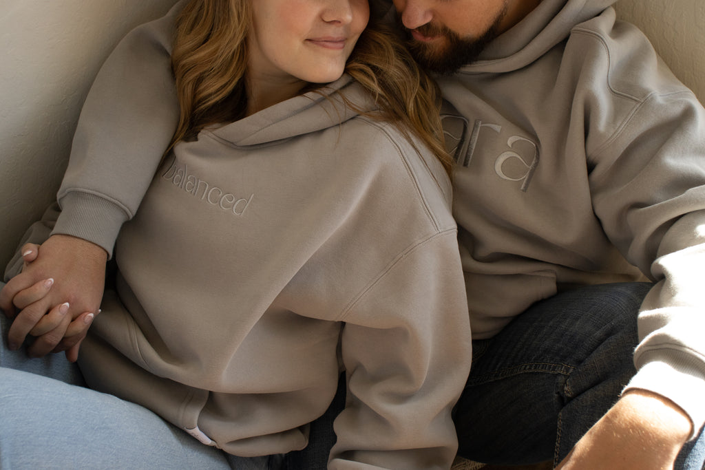 Two people wearing matching gray hoodies sitting close together.