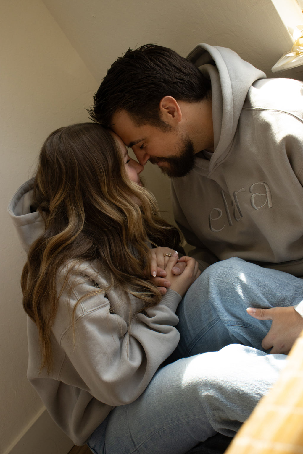 Two people sitting close together, embracing, in a cozy indoor setting.